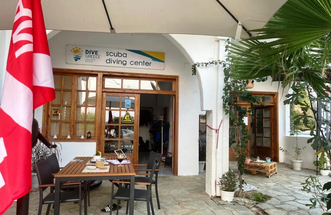 Exterior view of Dive Greece's scuba diving center in Halkidiki, featuring shop entrance, PADI signage, and outdoor setup.